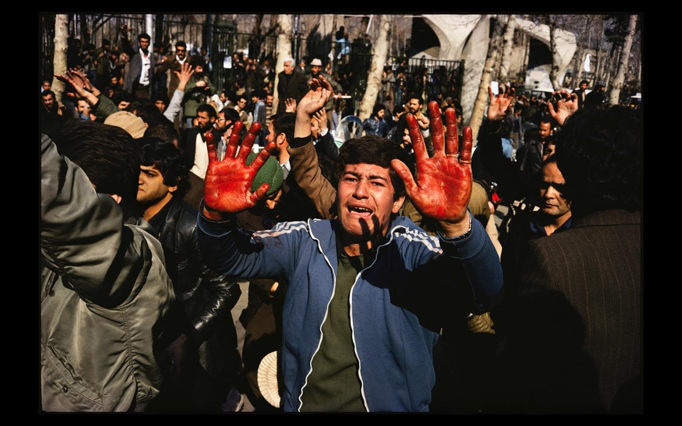 The day before Aystollah Khomeini's return to Iran after decades of exile,  members of the Army shot and killed a demonstrator, and his friends showed off his blood on their hands, showing that another martyr had fallen  1979 : Looking Back: 60 Years of Photographs : David Burnett | Photographer